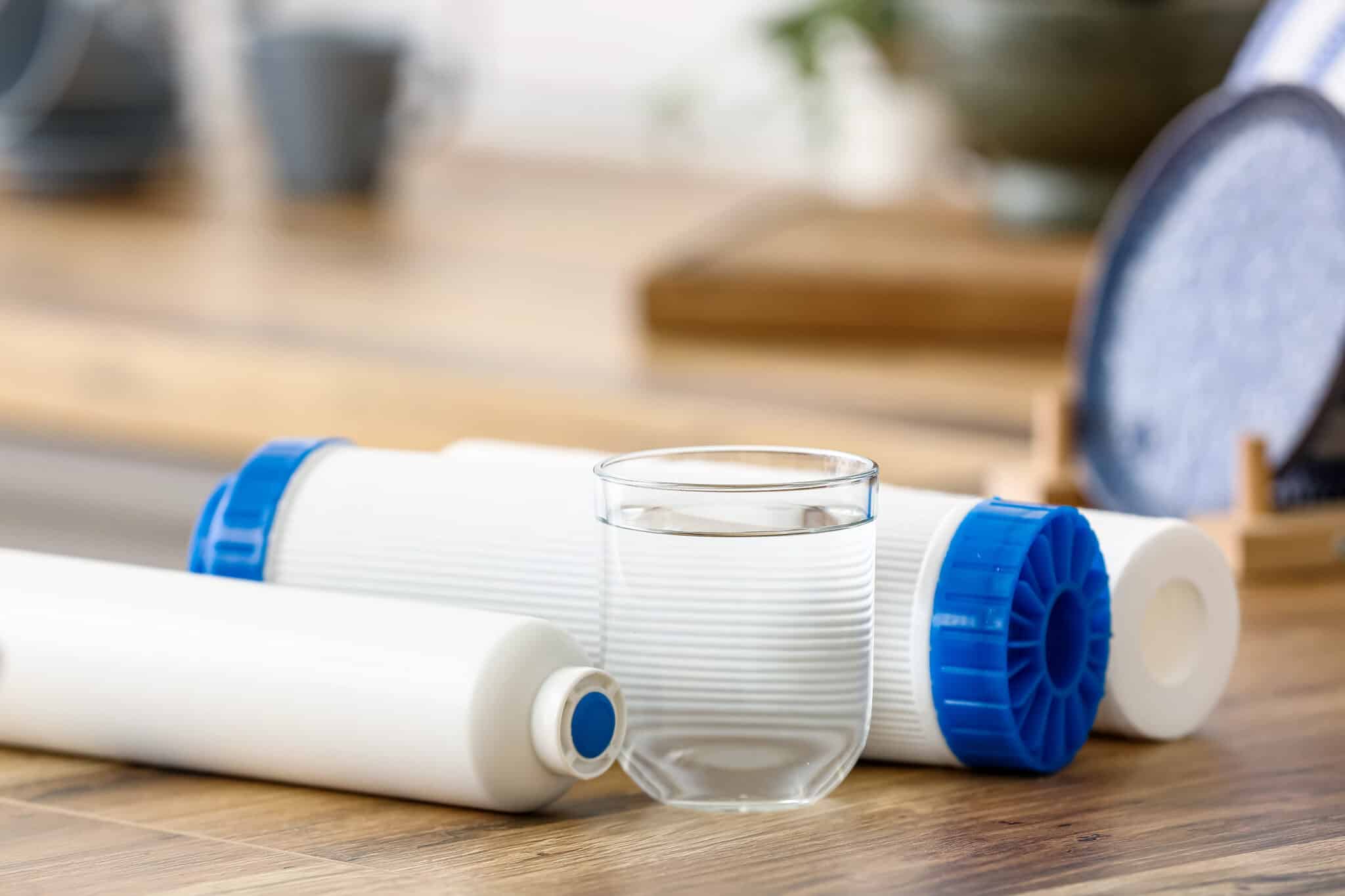 Glass of water with filters on wooden table in kitchen differents types de filtres à eau